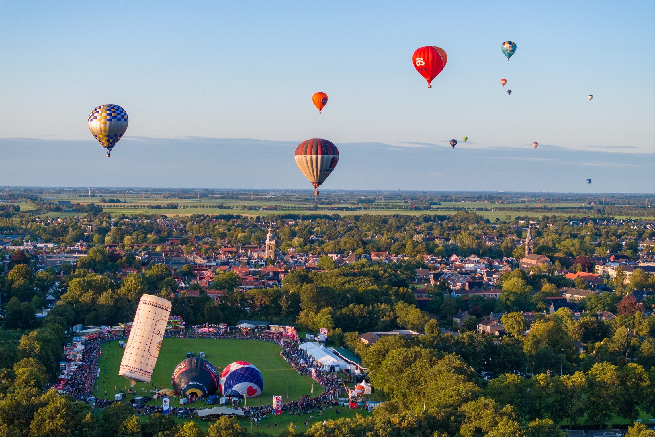 Luchtballonnen boven een dorp tijdens het gouden uur